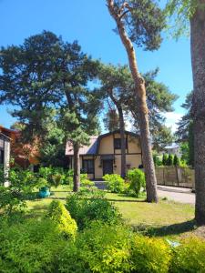 a house with trees in front of a yard at Classic Apartment in Jūrmala