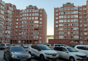 a parking lot with cars parked in front of tall buildings at Уютная квартира рядом с Батырмол in Pavlodar