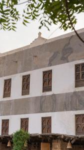 a white building with brown windows on it at نزل كوفان التراثي Koofan Heritage Lodge in Salalah