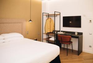 a bedroom with a bed and a desk with a television at H La Paloma in Barcelona