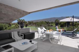 a patio with white tables and white chairs at KARAT Villa Calypso Costa Adeje in Adeje