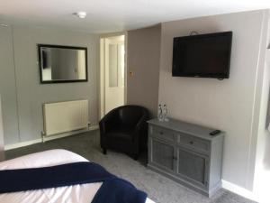 - une chambre avec un lit, une chaise et une télévision dans l'établissement OYO Auldgirth Inn, à Auldgirth