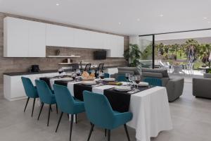 a dining room with a long table and blue chairs at KARAT Villa Calypso Costa Adeje in Adeje