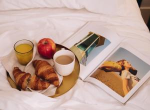 einen Frühstücksteller mit einem Apfel und einer Tasse Kaffee und ein Buch in der Unterkunft H La Paloma Boutique in Barcelona