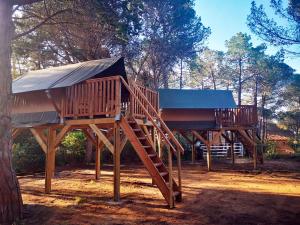 two wooden play structures sitting next to a tree at Camping Santa Elena in Lloret de Mar