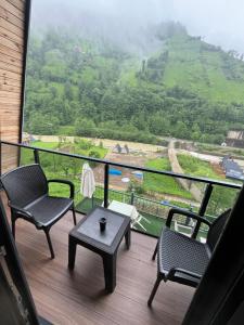 a balcony with chairs and a table and a view of a mountain at Çınar suit bungalov in Çamlıhemşin
