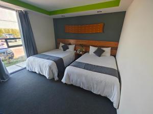 two beds in a room with a window at Hotel Brisas Express in San Cristóbal de Las Casas