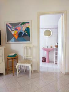 un baño con una pintura en la pared y un lavabo rosa en B&B Casa nel parco zona centrale en Teramo