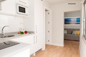 a white kitchen with a sink and a microwave at Hotel Apartamento Bajamar in Las Palmas de Gran Canaria