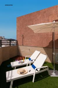 a patio with two chairs and an umbrella at Hotel Apartamento Bajamar in Las Palmas de Gran Canaria