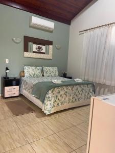 a bedroom with a bed with a green comforter at Hotel Chalés Gramado in Águas de Santa Barbara