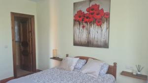 a bedroom with a bed with red flowers on the wall at Las Brisas - planta baja independiente in Marianes