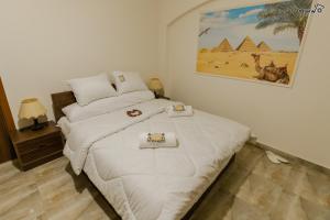 a bedroom with a white bed with a picture on the wall at Pyramids Golden Gate Hotel - Full Pyramids View & Roof Top in Cairo