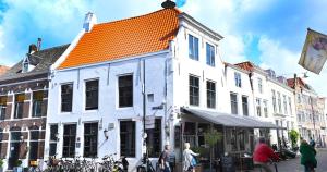 a white building with an orange roof on a street at De Bij Middelbrug in Middelburg