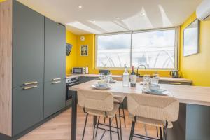 a kitchen with yellow walls and a table with chairs at Suites Kerlarros Clim et Parking face Gare et Port in Gujan-Mestras