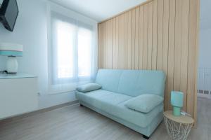 a living room with a blue couch and a window at Villa 25 in Cabra