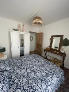 a bedroom with a blue and white bed and a mirror at Maison de village in Caux