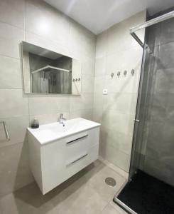 a white bathroom with a sink and a shower at Apartamento Duque Nájera (playa La Caleta, Cádiz) in Cádiz