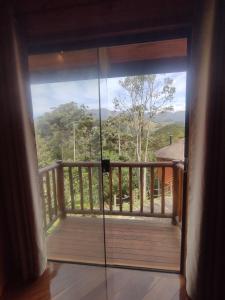 una puerta corredera de cristal que da a un balcón con vistas en Pousada Mirante do Céu, en Visconde De Maua