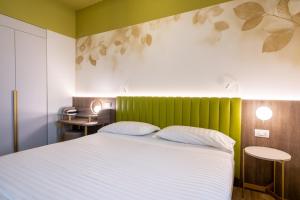 Schlafzimmer mit einem Bett mit einem grünen Kopfteil in der Unterkunft Hotel Regina Elena 57 & Oro Bianco SPA in Rimini