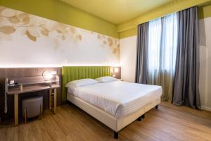 Schlafzimmer mit einem Bett, einem Schreibtisch und einem Fenster in der Unterkunft Hotel Regina Elena 57 & Oro Bianco SPA in Rimini