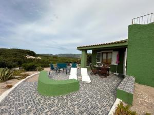 a green house with a patio with a table and chairs at Villa Verde in Badesi