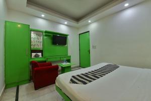 1 dormitorio con paredes verdes, 1 cama y 1 silla roja en Hotel Noida International - opposite Mercedes Showroom Noida Sector 11 en Nueva Delhi