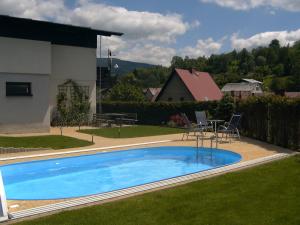 a swimming pool in the yard of a house at Apartmány Bulušek in Rokytnice nad Jizerou