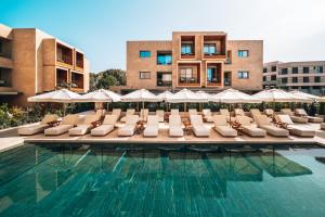 uma piscina com espreguiçadeiras e guarda-sóis em M Boutique Hotel - Designed for Adults em Pafos