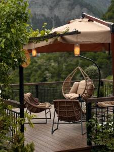 um pátio com um guarda-sol e cadeiras num deque em Hotel Borjomi Verde em Borjomi
