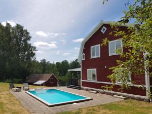 a swimming pool in front of a red house at Landhaus Lönneberga in Lönneberga