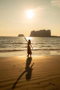 Una donna che cammina sulla spiaggia con la sua ombra di Modtanoi Paradise Homestay a Ban Bu Lu