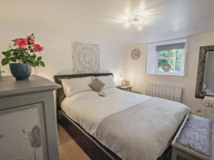 1 dormitorio con 1 cama y un jarrón de flores en 3 Bed in Ventnor 89972, en Niton