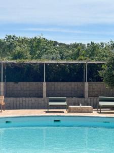 2 bancs installés à côté d'une piscine dans l'établissement Gandum Village, à Montemor-o-Novo