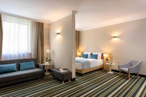 una camera d'albergo con letto e divano di Leonardo Hotel Budapest a Budapest