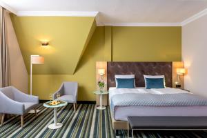 um quarto de hotel com uma cama e duas cadeiras em Leonardo Hotel Budapest em Budapeste