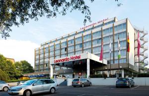 Un hotel con coches aparcados en un estacionamiento. en Leonardo Hotel Mönchengladbach, en Mönchengladbach