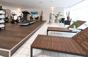 un gimnasio con bancos y una cinta de correr y equipos de ejercicio en Leonardo Hotel Mönchengladbach, en Mönchengladbach