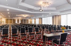 Cette grande chambre comprend des rangées de chaises et de tables. dans l'établissement Leonardo Hotel Munich Arabellapark, à Munich