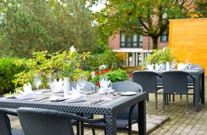 a set of tables and chairs with plates and glasses at Leonardo Hotel Mönchengladbach in Mönchengladbach