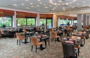 un restaurante con mesas, sillas y ventanas en Leonardo Royal Hotel Baden- Baden en Baden-Baden