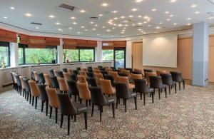 uma sala de conferências com uma fila de cadeiras e um ecrã em Leonardo Royal Hotel Baden- Baden em Baden-Baden