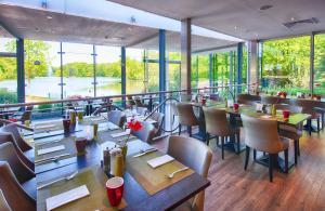 ein Restaurant mit Tischen und Stühlen und großen Fenstern in der Unterkunft Leonardo Royal Hotel Köln - Am Stadtwald in Köln