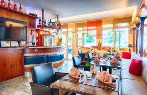 a restaurant with tables and chairs and a bar at Leonardo Hotel Muenchen City West in Munich