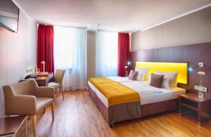 a hotel room with a large bed and a chair at Leonardo Hotel München City Center in Munich