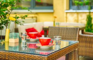 a glass table with red cups and plates on it at Leonardo Hotel München City Center in Munich +21 photos
