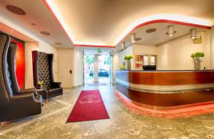 eine Lobby mit einer Bar mit einem roten Teppich in der Unterkunft Leonardo Hotel Muenchen City West in München