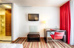 a hotel room with a desk and a red curtain at Leonardo Hotel Muenchen City West in Munich
