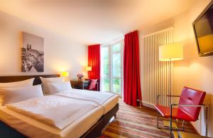 een hotelkamer met een bed en een rood raam bij Leonardo Hotel München City West in München