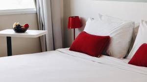 um quarto com 2 camas com almofadas vermelhas e uma mesa em Mercure Jundiai Shopping em Jundiaí
